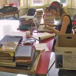 A volunteer sitting at a table surrounded by books